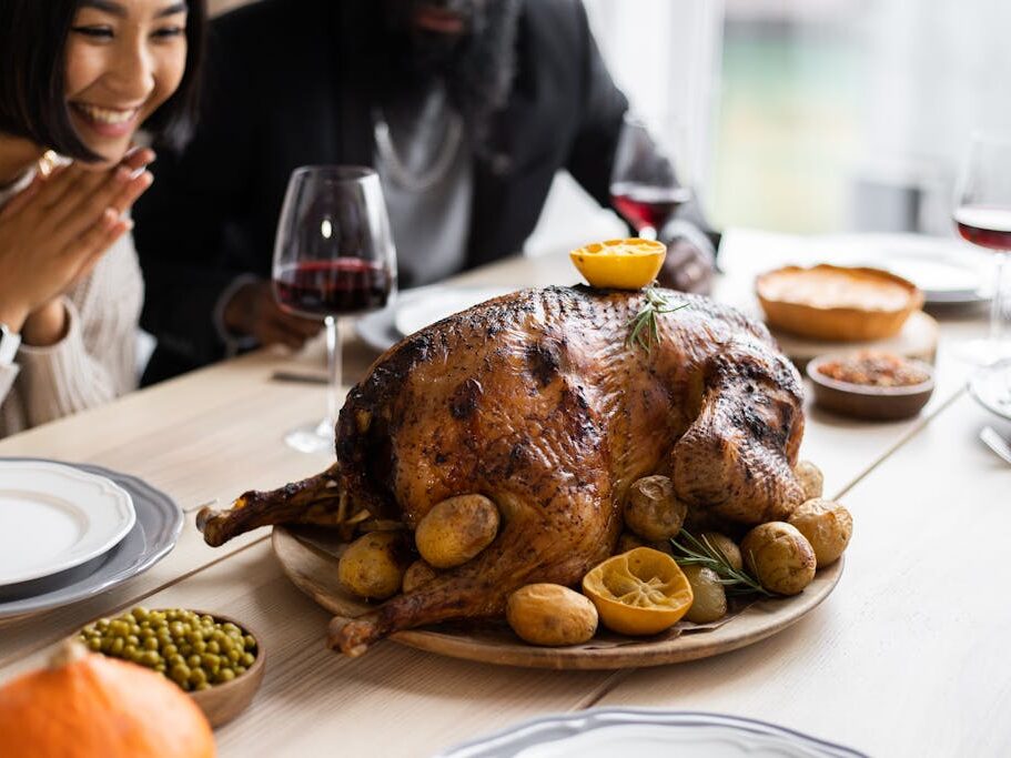 Cheerful multiethnic couple sitting at table with roasted turkey